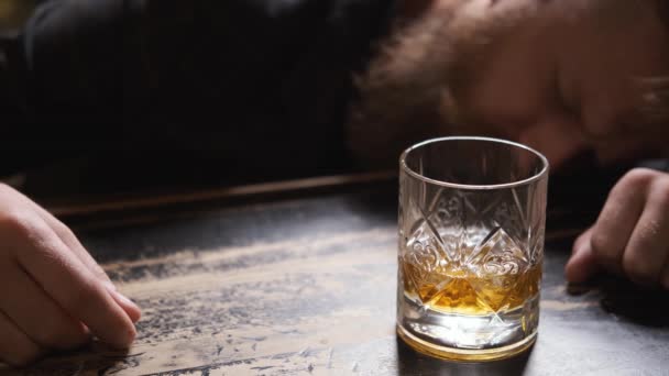 Пьяный мужчина заснул в баре со стаканом виски, выглядит плохо и расстроен — стоковое видео