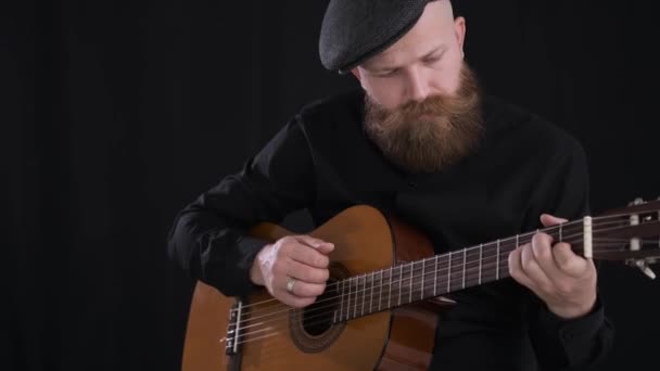 Человек играет на гитаре, молодой артист, акустической гитаре, черном фоне — стоковое видео