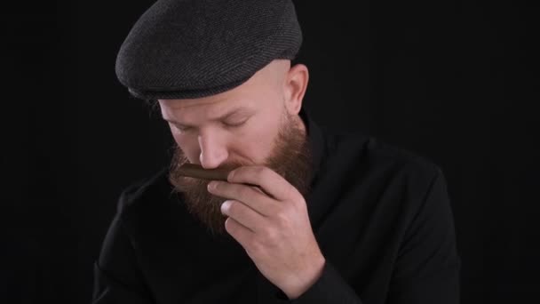 Criminal hombre en gorra olfatea cigarro en negro background.close hasta, caucásico — Vídeos de Stock