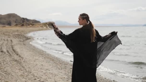 Menina oriental caminha ao longo das margens de um rio, vestido nacional preto — Vídeo de Stock