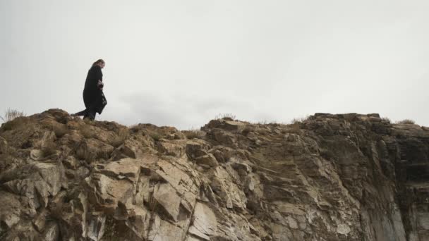 Fille marchant sur le bord de la falaise, en vêtements nationaux noirs, en robe de deuil — Video