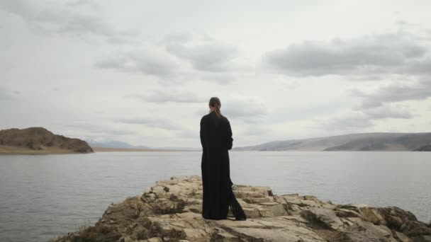 Mädchen Reisende am Rande einer Klippe an der Spitze eines Berges. Großer See. — Stockvideo