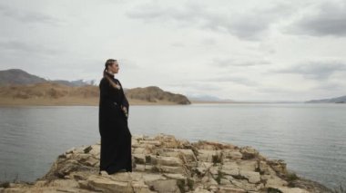 Kadın dağın tepesindeki uçurumun kenarına yürür. Arkadan bakar.