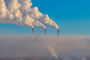 Mavi gökyüzüne karşı enerji santrallerinin borularından çıkan duman