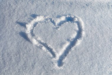 Güneşli bir günde karda kalp çizmek