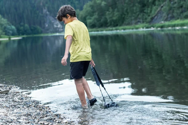 Niño Orilla Del Río Arrastra Una Cámara Detrás Través Del — Foto de Stock