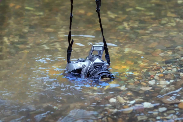 SLR camera submerged on the river. concept of waterproof devices and equipment