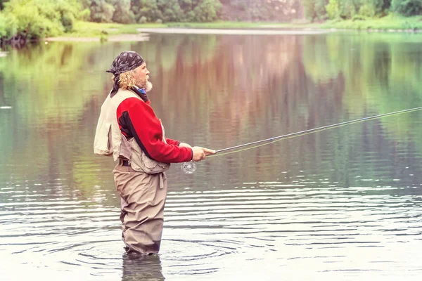 一个留着胡须 头戴头巾 手里拿着钓竿 站在河边的男人 夏天钓鱼杆 — 图库照片