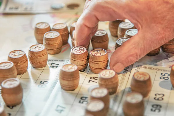 Russian lotto, wooden barrels with numbers are placed on the cards, a hand reaches for the barrels