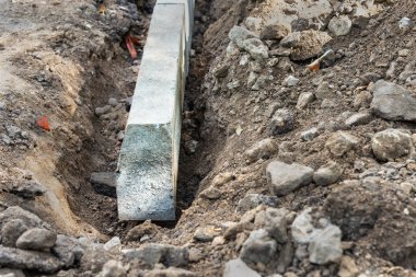Taşların, kumların ve çakılların arasında toprak bir hendekte yol sınırı