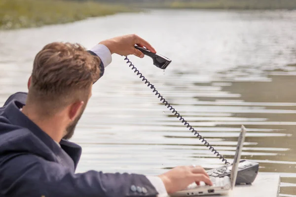 沼の中のテーブルの上のビジネススーツの男携帯電話電話電話電話から滴り落ちる水 — ストック写真