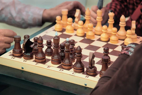 chessboard with pieces surrounded by sedentary players