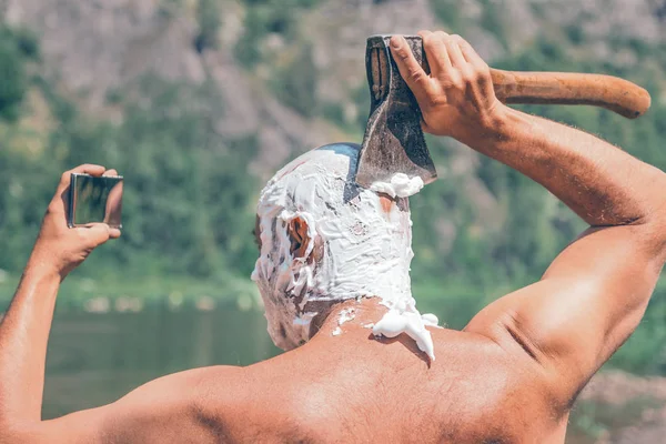 man shaves his head with an ax, the concept of masculinity and brutality