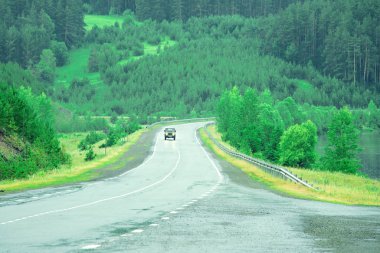 Dağlar ve ormanlarla çevrili bir göl boyunca otomobil yolu.