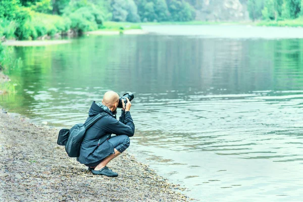 Bald Man Jacket Backpack Camera Sits River — Stock Photo, Image