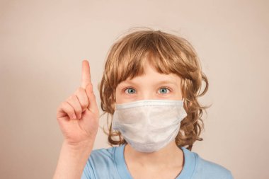 Mavi tişörtlü, tıbbi maske takan ve parmağını fotokopi aletiyle gösteren sarışın çocuk. Virüs enfeksiyonu kavramı