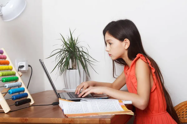 School girl at home on distance education, homeschooling and doing homework at laptop. E-learning, web lesson concept