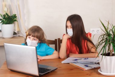 Çocuklar tıp maskeli, uzaktan eğitimli çocuklar evde karantinadayken internetten web sitesi izliyorlar. Evde eğitim ve ev ödevi yapmak, E-öğrenme, web ders kavramı