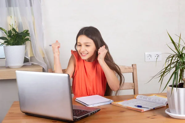 Self-isolated girl talking to teacher online and doing homework, watching webinar at laptop.  Distance education, homeschooling, E-learning at home during quarantine concept