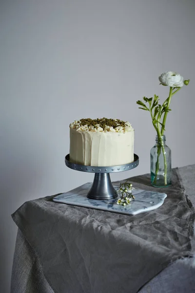 A cake on the cakestand decorated with nuts and ground rosemary — Stock Photo, Image
