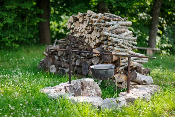 Un calderone e un mucchio di legna da ardere sul prato — Foto Stock