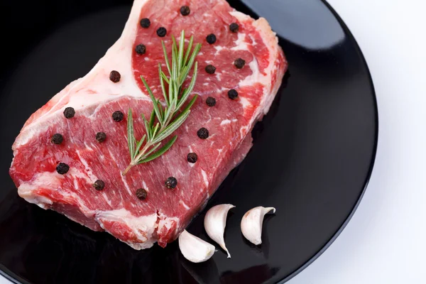 Raw red sirloin steak with rosemary, garlic , pepper