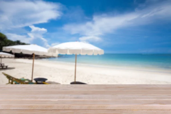 Mesa de madera sobre fondo azul borroso y playa de arena blanca — Foto de Stock