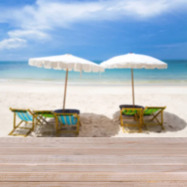 Mesa de madera sobre fondo azul borroso y playa de arena blanca — Foto de Stock
