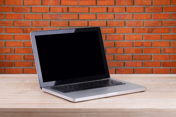 Front view of the laptop is on the work table brick background — Stock Photo, Image