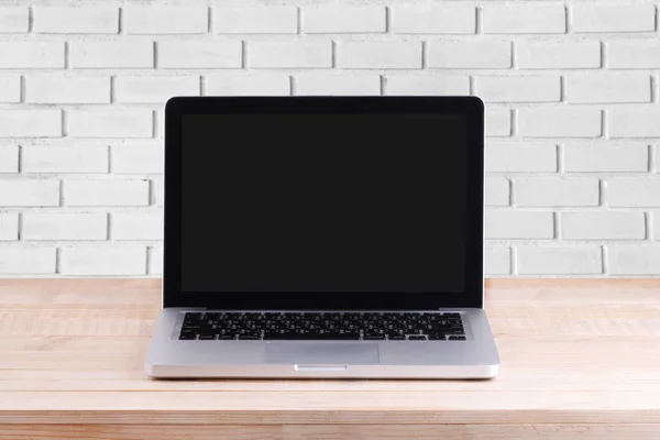 Front view of the laptop is on the work table brick background