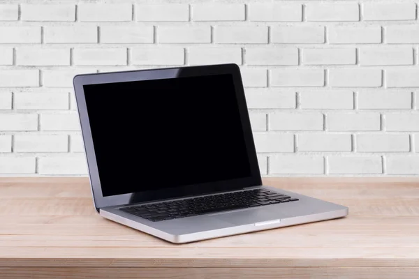 Vorderseite des Laptops ist auf dem Arbeitstisch Backsteinhintergrund — Stockfoto
