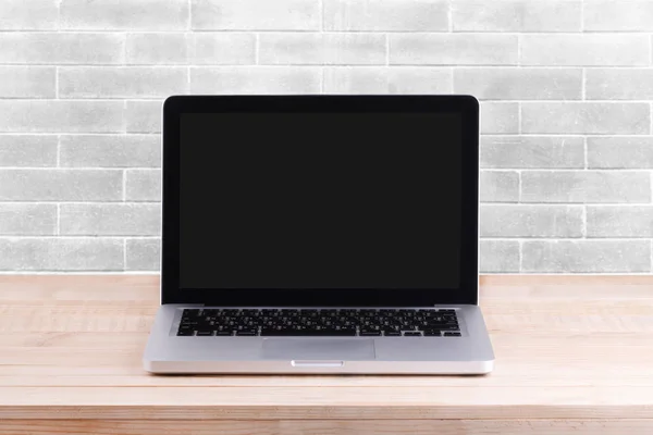 Vista frontal de la computadora portátil está en la mesa de trabajo fondo de ladrillo blanco —  Fotos de Stock