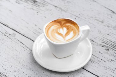 Latte üzerinde beyaz ahşap masa kahve bir fincan