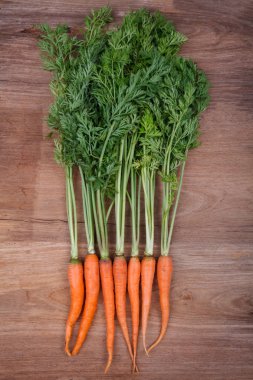 ahşap arka plan üzerinde demet taze havuç yeşil yaprakları