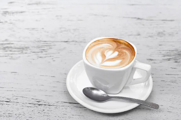 Uma xícara de café com leite na mesa de madeira branca — Fotografia de Stock