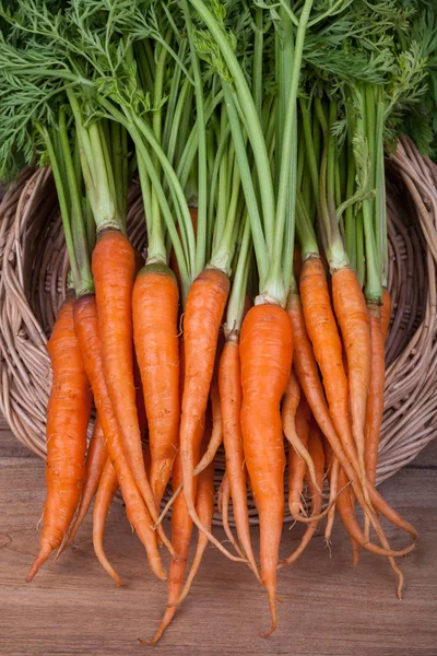 Manojo de zanahorias frescas con hojas verdes sobre fondo de madera — Foto de Stock