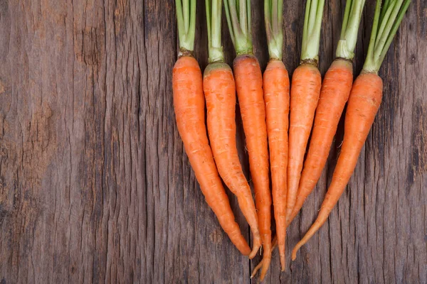 Куча свежей моркови с зелеными листьями на деревянном фоне — стоковое фото