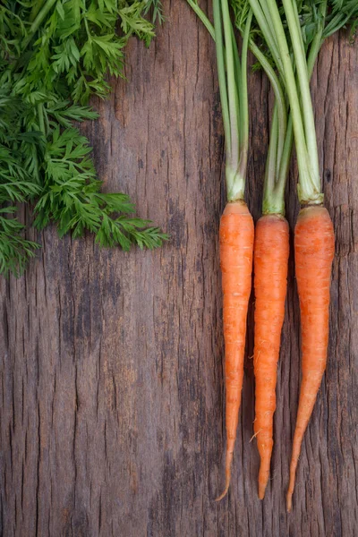 Куча свежей моркови с зелеными листьями на деревянном фоне — стоковое фото