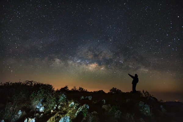 Un hombre está de pie junto a la galaxia de la Vía Láctea apuntando a un bri — Foto de Stock