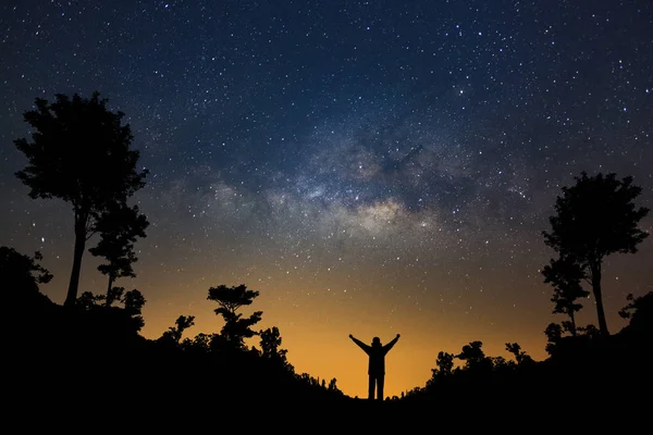 Via Lattea galassia e silhouette di un uomo felice in piedi nei fori Foto Stock