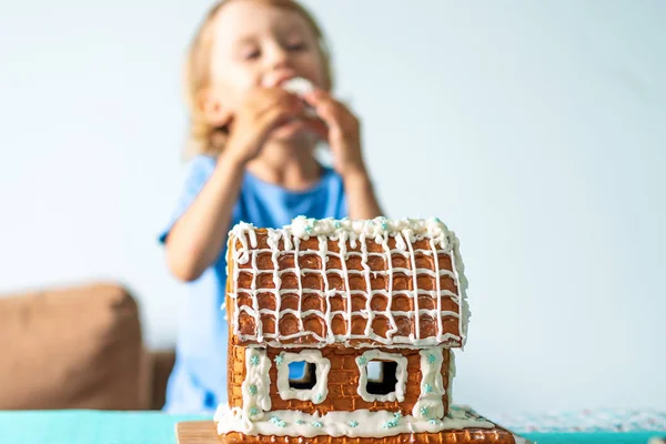 Niedlichen kleinen Jungen isst Lebkuchenhaus und Spaß haben. Kinder genießen Weihnachtstraditionen. — Stockfoto