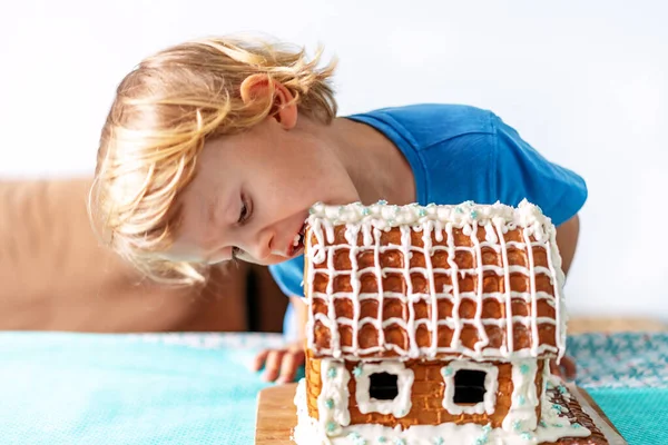 Niedlichen kleinen Jungen isst Lebkuchenhaus und Spaß haben. Kinder genießen Weihnachtstraditionen. — Stockfoto