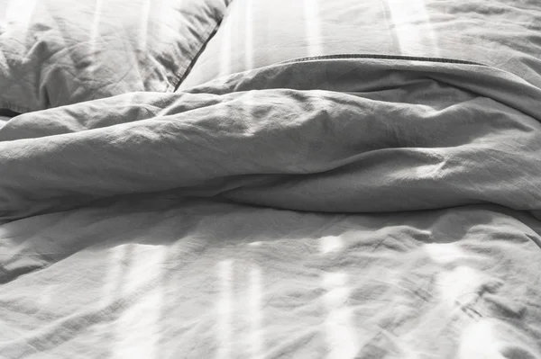 Грязная кровать с двумя подушками, серым постельным бельем — стоковое фото