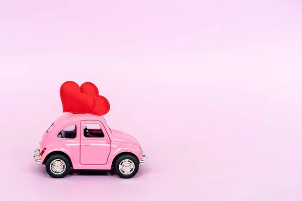 Carro de brinquedo retro rosa entregando coração artesanal para o dia dos namorados — Fotografia de Stock