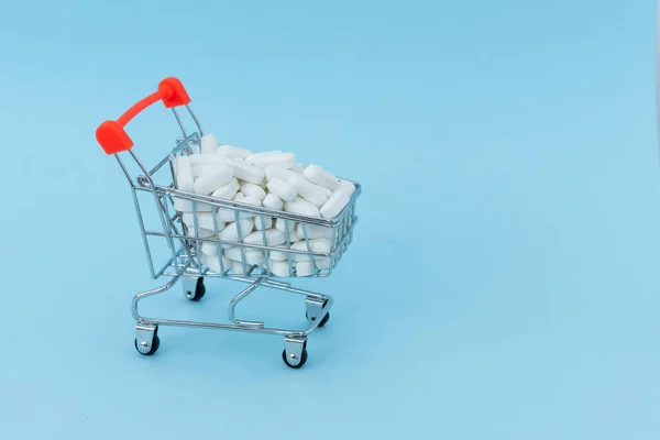 Carrinho de compras cheio de medicamento, isolado em fundo azul . — Fotografia de Stock