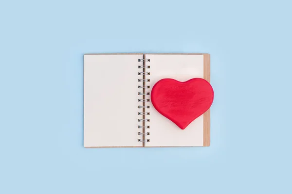 Červená dřevěná láska srdce na otevřeném notebooku na modrém pozadí — Stock fotografie