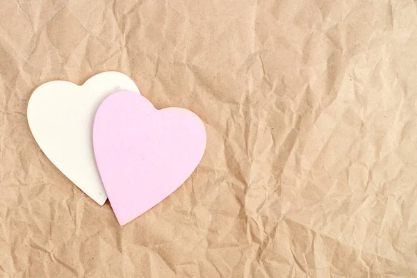 Dvě dřevěná srdce na starý zmačkaný řemeslný papír. — Stock fotografie