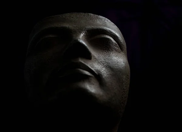 Ancient Greek bust that depicts the face of a female figure. Black background studio photography.