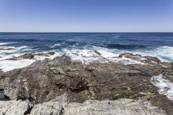 Rock on the coast. Ocean waves surf on the coast cliff.