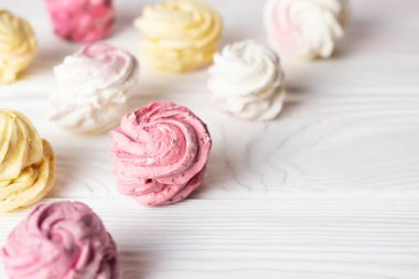 Farklı tat ve renklere sahip lezzetli ev yapımı şekerlemeler, pembe, beyaz ve sarı. Beyaz masaya yaklaş.